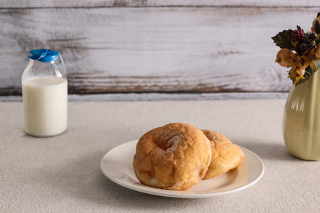 Two donuts on a plate and a bottle of milk on a wooden backgroundの写真素材