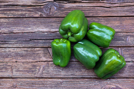 Green bell peppers on a wooden background. Top view. Copy space.