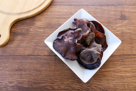 Cloud ear mushrooms on a crockery isolated on a wooden background.の写真素材