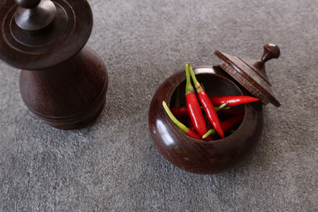 Red peppers in a wooden tableware on a stone pattern table.
