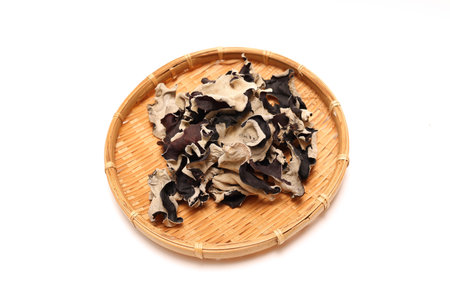 Dried cloud ear mushrooms on a bamboo colander isolated on a white background.の写真素材