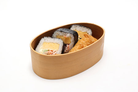 Sushi roll and Inarizushi in a wooden lunch box isolated on a white background.の写真素材