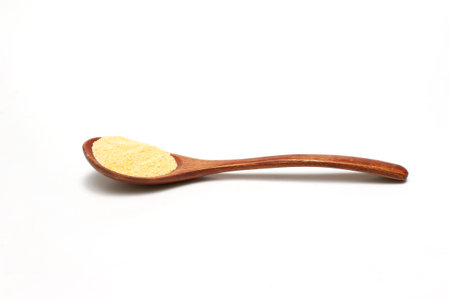 Cornmeal on a wooden spoon isolated on a white background.の写真素材
