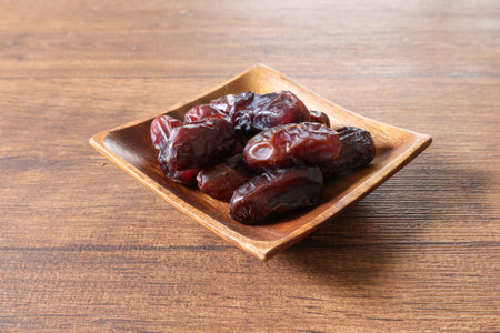 Dates fruit in a bowl on wooden background. Top view.の写真素材