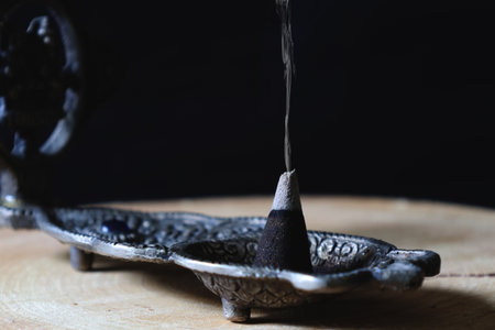 Cone incense burning on an incense burner.の写真素材