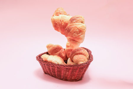 Croissants in a basket isolated on a pink background.