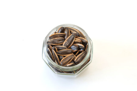 Sunflower seeds in a glass bottle isolated on a white background.の写真素材