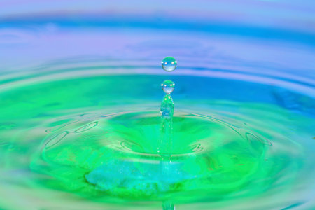 Water drop splashing on the surface of the water in a blue background.の写真素材