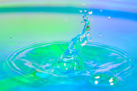 Water drop splashing on the surface of the water in a blue background.の写真素材