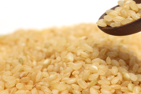 Brown rice isolated on a white background with a wooden spoon.の写真素材