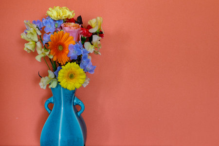â¤arious kind of flowers in a blue vase isolated on a orange wall.の写真素材
