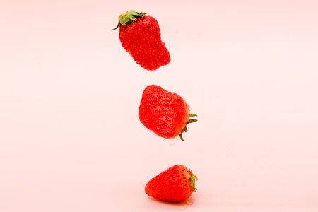 strawberry falling on a pink background with copy space for textの写真素材