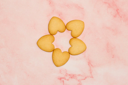 cookies in the shape of a heart on a pink marble backgroundの写真素材
