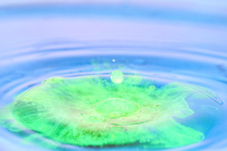 Water drop splashing on the surface of the water in a blue background.の写真素材