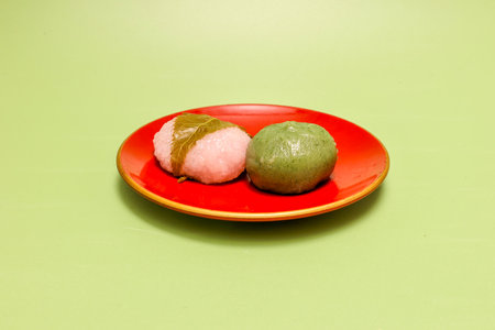 Japanese rice flour dumpling mixed with mugwort and Rice cake with bean paste wrapped isolated on a green background.の写真素材