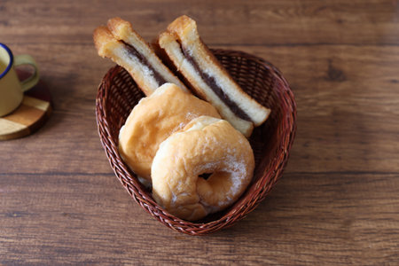 Fried bread sandwiches with bean jam and doughnut in a basket on a wooden table.