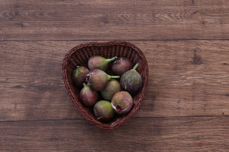Ripe figs in a basket on a wooden background. Top view
