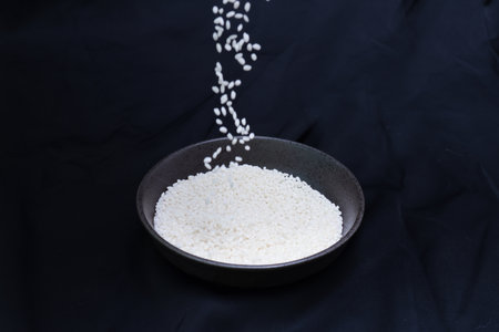 Sticky rice in a pottery bowl isolated on a black background.の写真素材