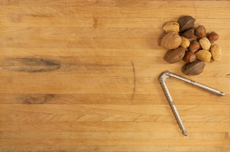 Mixed nuts sit on a butcher block counter with a metal nutcracker