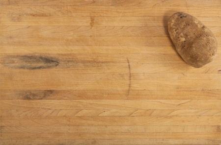 A russet potato sits on a worn butcher block counterの写真素材