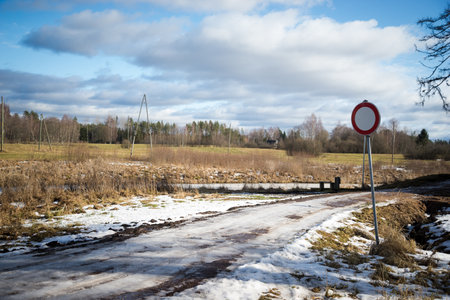 dirty mud road in winter with water on the surface. sunny day with snowの写真素材