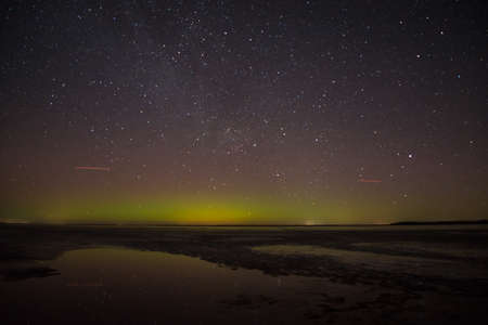 Northern lights (Aurora Borealis) over the lake and hills. Aurora at night in the sky in the north.の写真素材