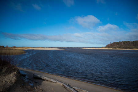 The river Gauja Latvia flows into the Baltic Sea. Blue sky with cumulus clouds on a warm spring day.