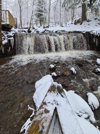 Winter landscape with forest river. Valley of waterfalls. Snow-covered trees on the river bank. A submerged log in the river. Winter landscapeの写真素材