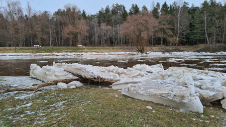 Pieces of ice on the river bank in sunny weather with forest landscape. Blue skyの写真素材