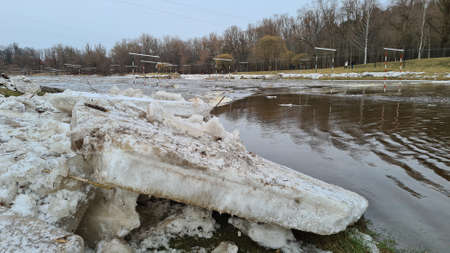 Pieces of ice on the river bank in sunny weather with forest landscape. Blue skyの写真素材
