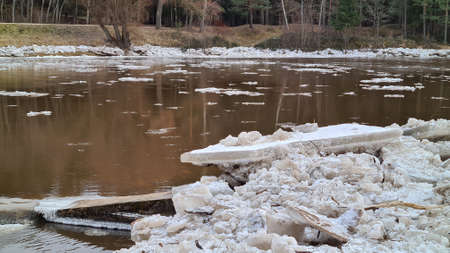 Pieces of ice on the river bank in sunny weather with forest landscape. Blue skyの写真素材