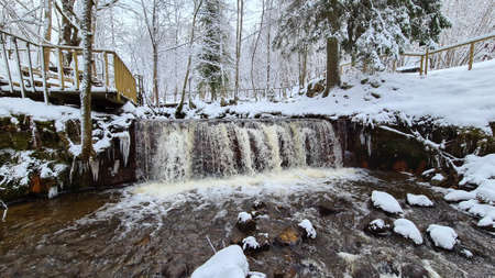 Winter landscape with forest river. Valley of waterfalls. Snow-covered trees on the river bank. A submerged log in the river. Winter landscapeの写真素材