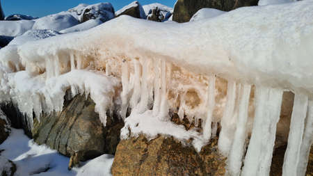 pile of snowy rocks by the sea on a sunny winter day with a blue sky. Winter landscapeの写真素材