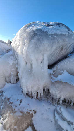 Close-up of frozen sea stones by the sea. cool winter day. A layer of white snow over the stones