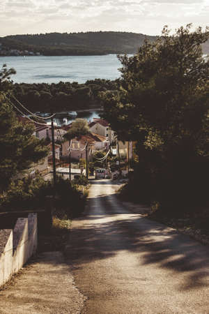 Beautiful street view in Croatia. The street goes down the hill. mountains and water can be seen in the distance. Summer landscapeの写真素材
