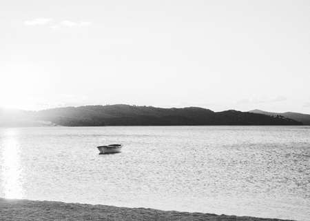 Beach by the sea at sunset with a lonely abandoned boat in the water. Mountains in the background. Travel Croatia. Summer landscapeの写真素材