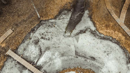 An aerial shot over a park with a pond with a small bridge. It is a beautiful autumn day from a bird's eye view. The pond is frozen. Drone shotの写真素材