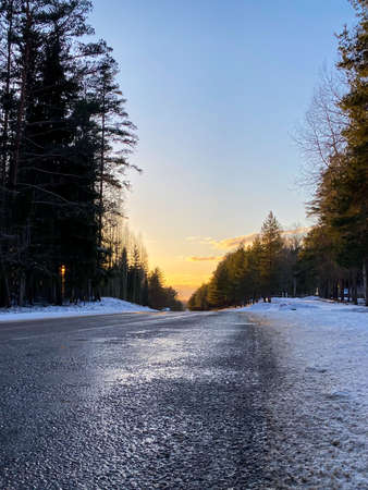 Winter road through a snowy forest at sunset. Winter landscape