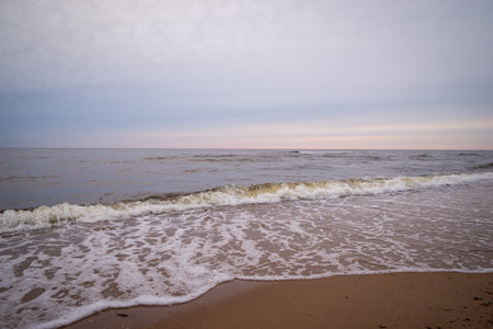 sea shore in summer beach with blue water waves and sand with rocks and pebblesの写真素材