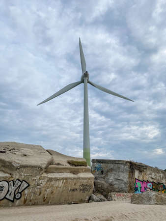 White wind generator against a dramatic cloudy sky at the concrete blocksの写真素材