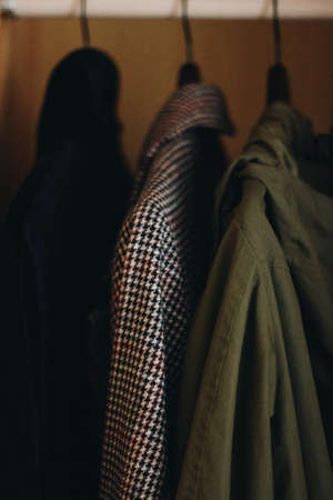 Black, green and white coat in the closet. White checkered coat close-up with black lines