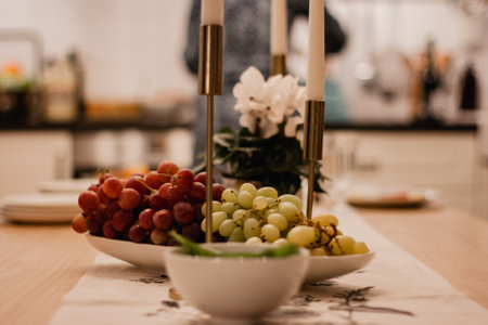 Festive table with burning candles gold candlestick. Red and green grapes in a white bowl.の写真素材