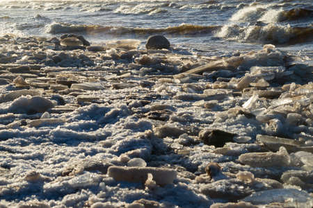 frozen sea side beach panorama in winter with lots of ice and snow in late evening
