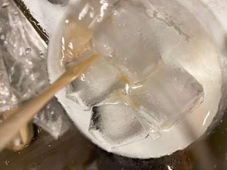 Ice cube in a white glass, sprinkled with grapefruit juice, isolated on a gray background, top viewの写真素材