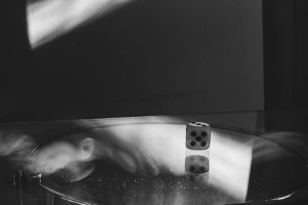 One rolling die with the number five visible on the glass surface in glare. Long exposure with blurred light.の写真素材