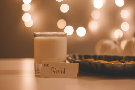 Christmas greeting card with gingerbread in a bowl with a glass of milk next to it, Christmas bokeh lights in the backgroundの写真素材
