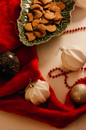 Christmas greeting card with gingerbread in a green dish surrounded by a red Santa's hat and...