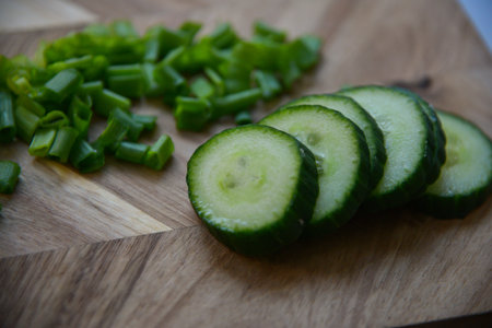 green fresh sliced onions with green sliced cucumber on a wooden boardの写真素材