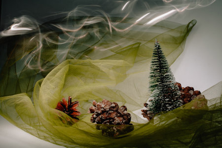 Christmas and New Year's card with a small artificial green tree and cones on a table with a colorful background in which lights shine, creating a bokeh background.の写真素材