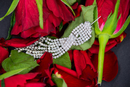Close-up of a woman's diamond jewelry in red rose flowers on a black background. View from the top.の写真素材